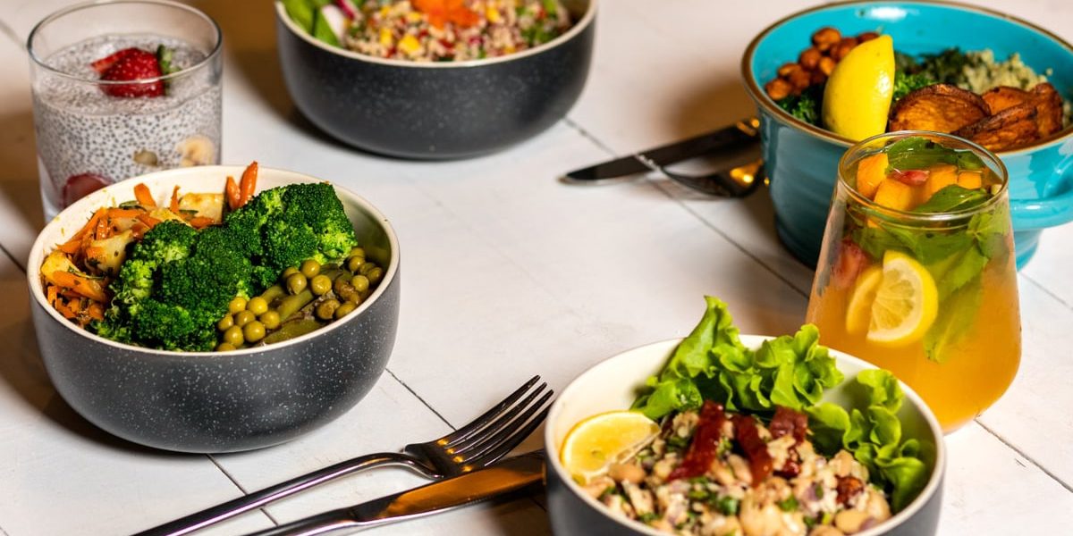 A vibrant assortment of healthy bowls and drinks showcasing fresh ingredients like broccoli and citrus.