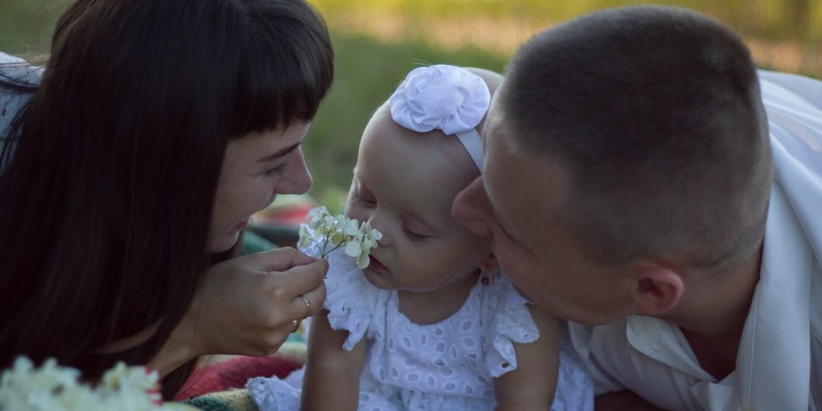 A loving family moment with parents and baby at a sunny outdoor picnic.
