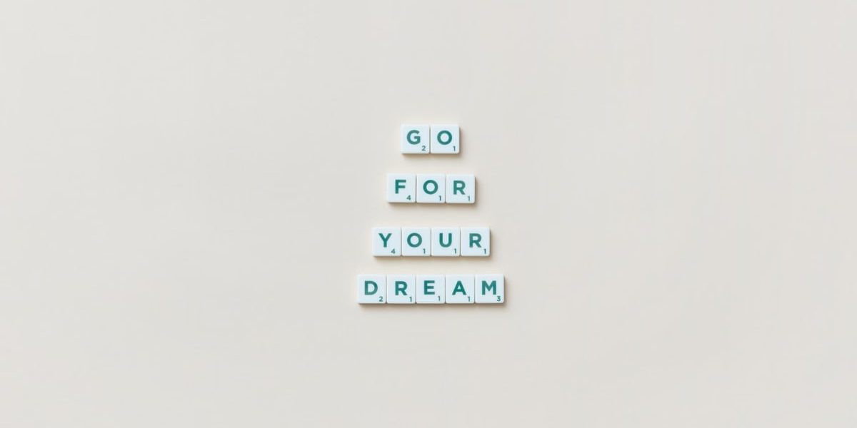 Inspirational text 'Go For Your Dream' made from Scrabble tiles on a plain background.
