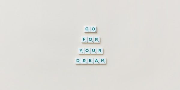 Inspirational text 'Go For Your Dream' made from Scrabble tiles on a plain background.